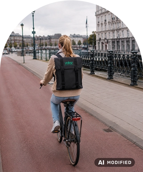 Kvinna med ryggs&auml;ck som cyklar i en stad.